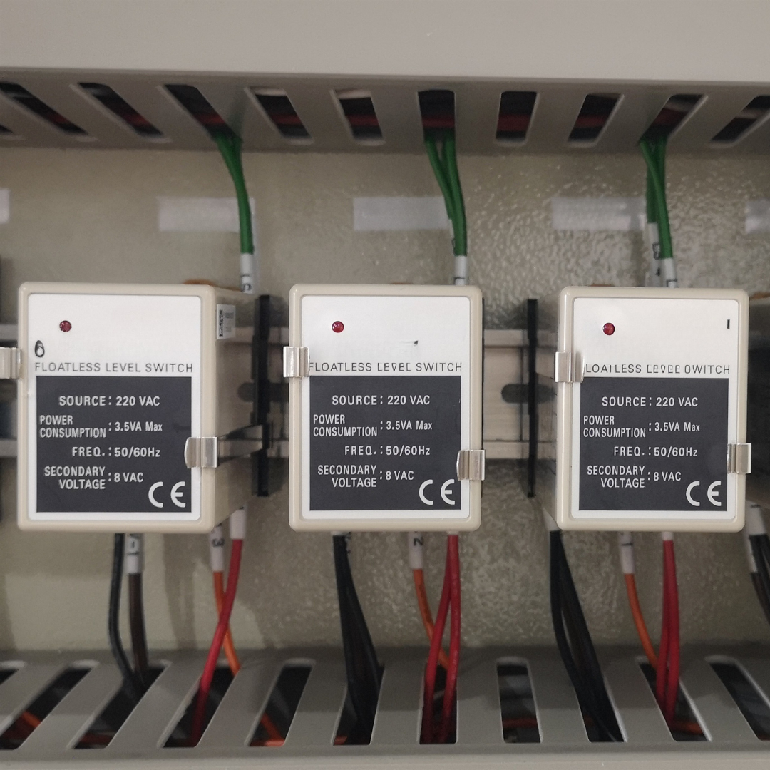 Three floatless level switch units wired inside a cooling water system control panel